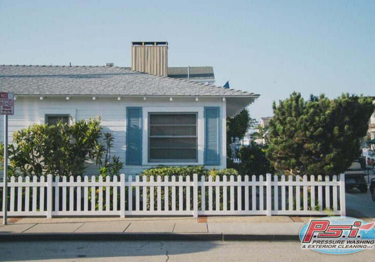 White fence in front of a white and blue house
