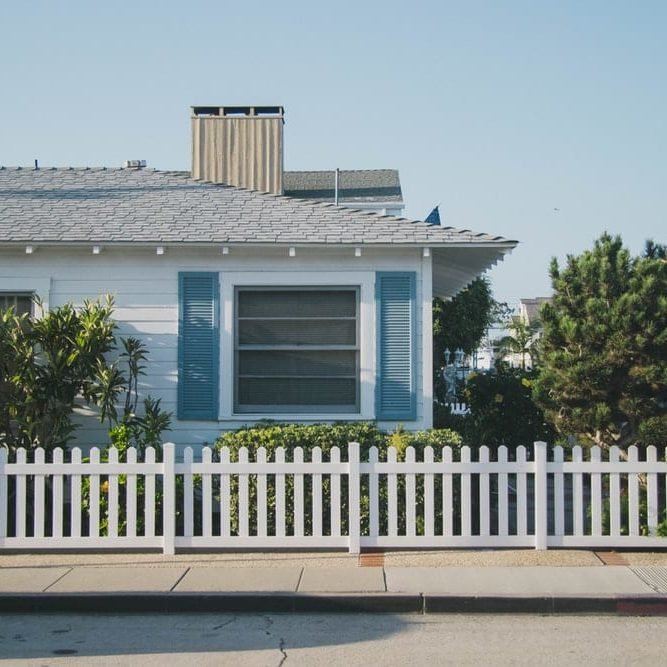 White fence in front of a white and blue house